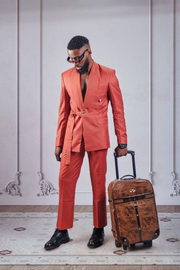 Man in a rust belted suit with a suitcase