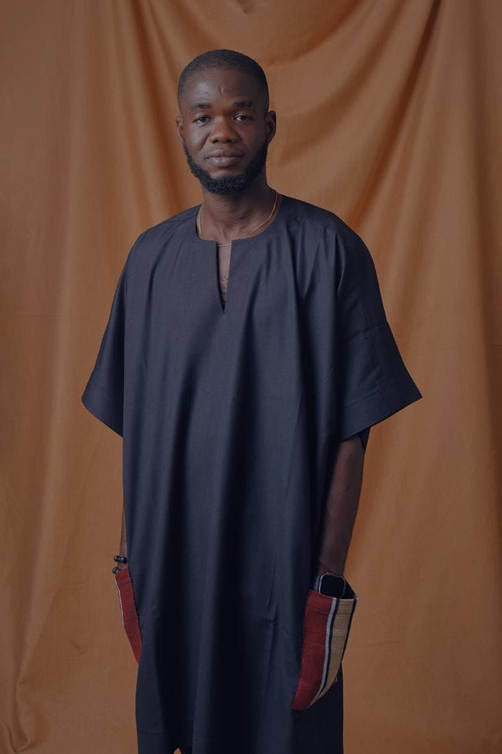 Man in a navy agbada-lite with striped aso-oke pockets