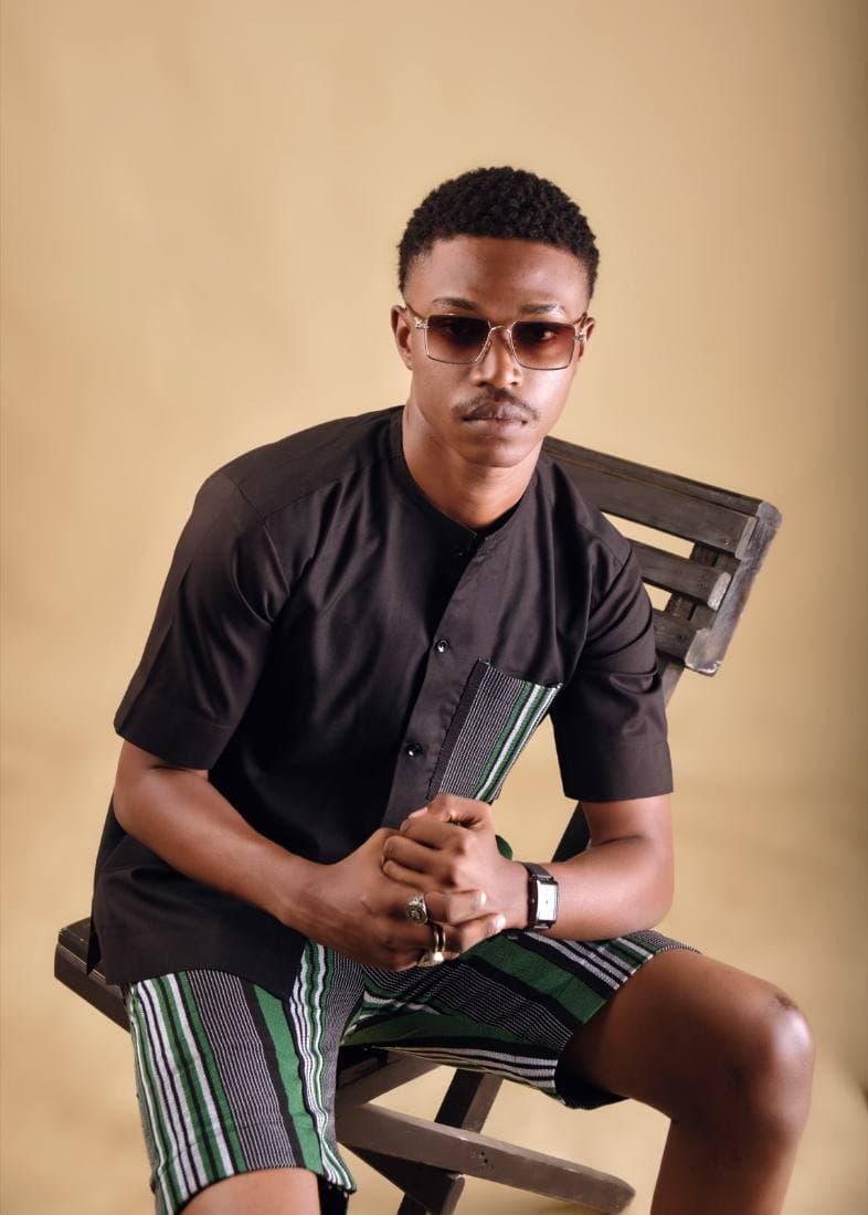 Man in a black shirt and green aso-oke shorts